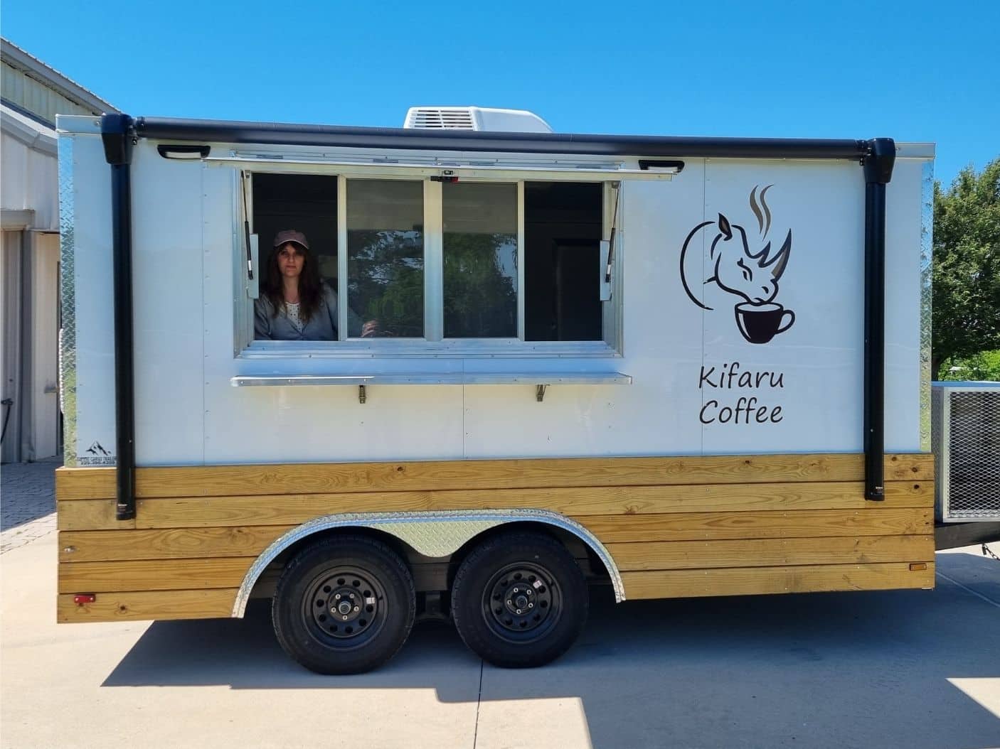 Kifaru Coffee Dripping Springs The Kifaru Coffee mobile trailer with rhino logo, wood panelling, and open service window on a sunny day.