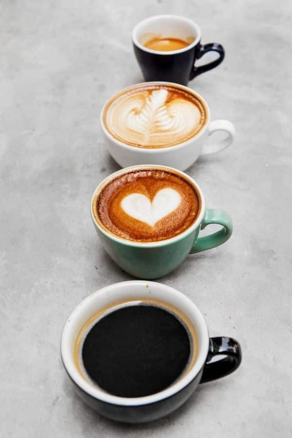 Four coffee drinks in a diagonal row - americano, cappuccino with heart latte art, latte with rosetta art, and an espresso shot - representing the full Kifaru Coffee menu