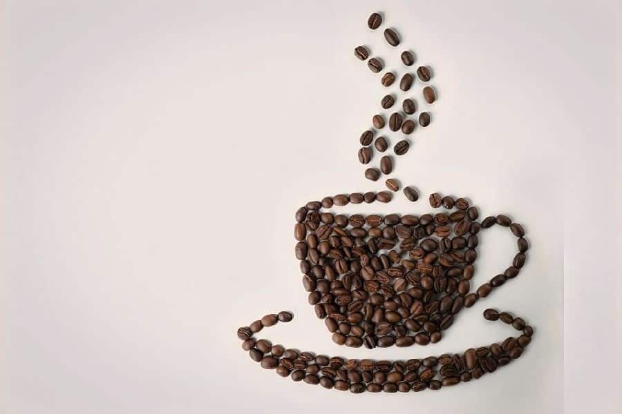 A steaming coffee cup shape created from whole roasted coffee beans on a light background