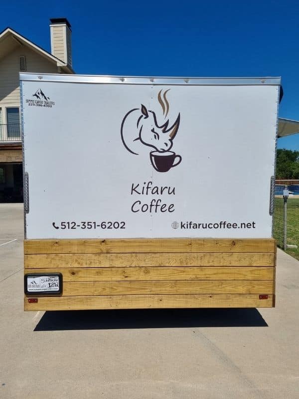 The Kifaru Coffee trailer showing the brand logo, contact number, and website on a white panel above a natural wood base