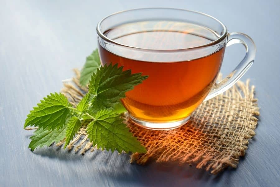 A glass cup of hot tea with fresh mint leaves on a hessian coaster